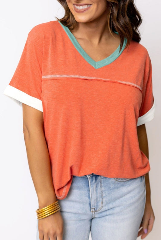 Orange tee with aqua trim around v-neck & exposed seams