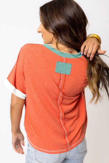 Orange tee with aqua trim around v-neck & exposed seams